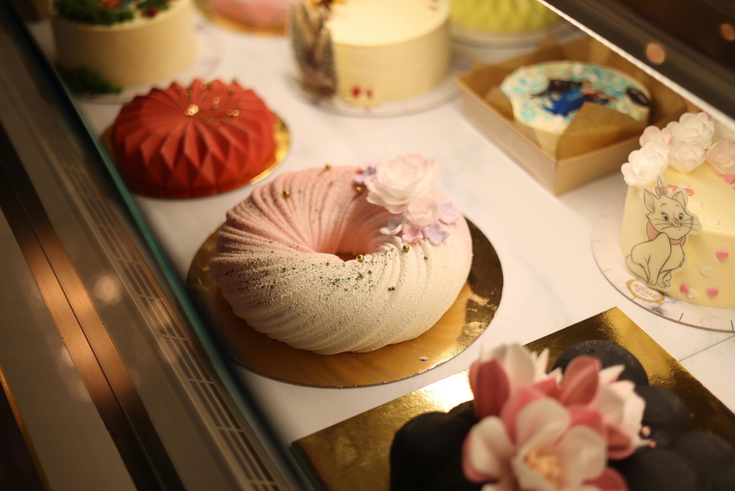 A luxurious selection of beautifully designed cakes in a bakery display case.